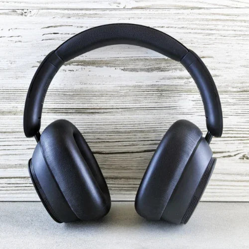 Black over-ear wireless headphones with cushioned ear pads on light wood background